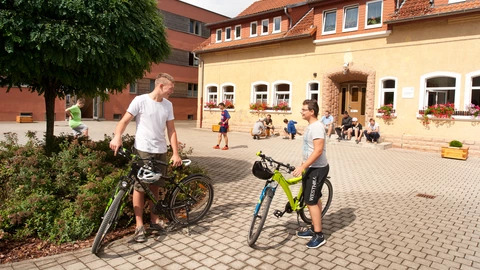 Zwei Jugendliche stehen im Innenhof neben ihren Fahrrädern.