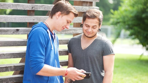  Zwei Jugendliche schauen auf ein Smartphone.