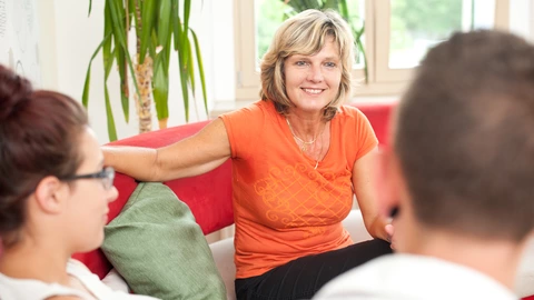 Eine Pädagogin unterhält sich mit zwei Jugendlichen.