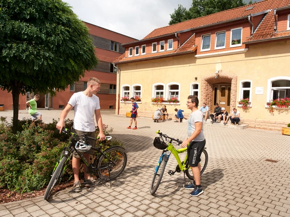 Zwei Jugendliche stehen im Innenhof neben ihren Fahrrädern.