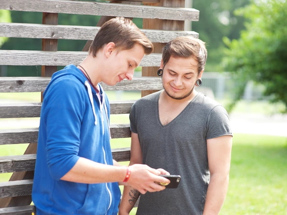  Zwei Jugendliche schauen auf ein Smartphone.