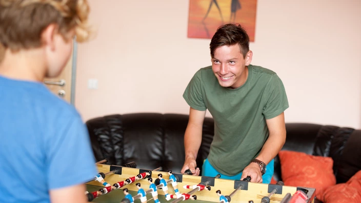  Zwei Jugendliche spielen zusammen am Tischkicker.