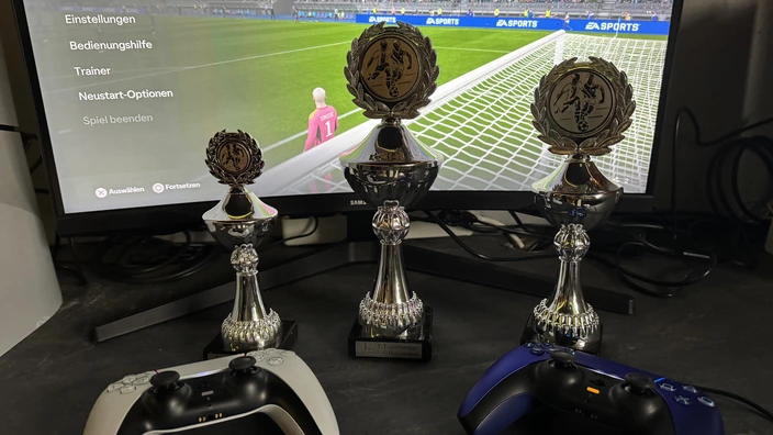 Drei Pokale vor einem Monitor